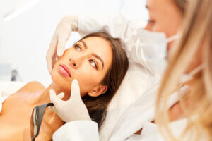 Clinician examining a patient’s face during a cosmetic consultation.