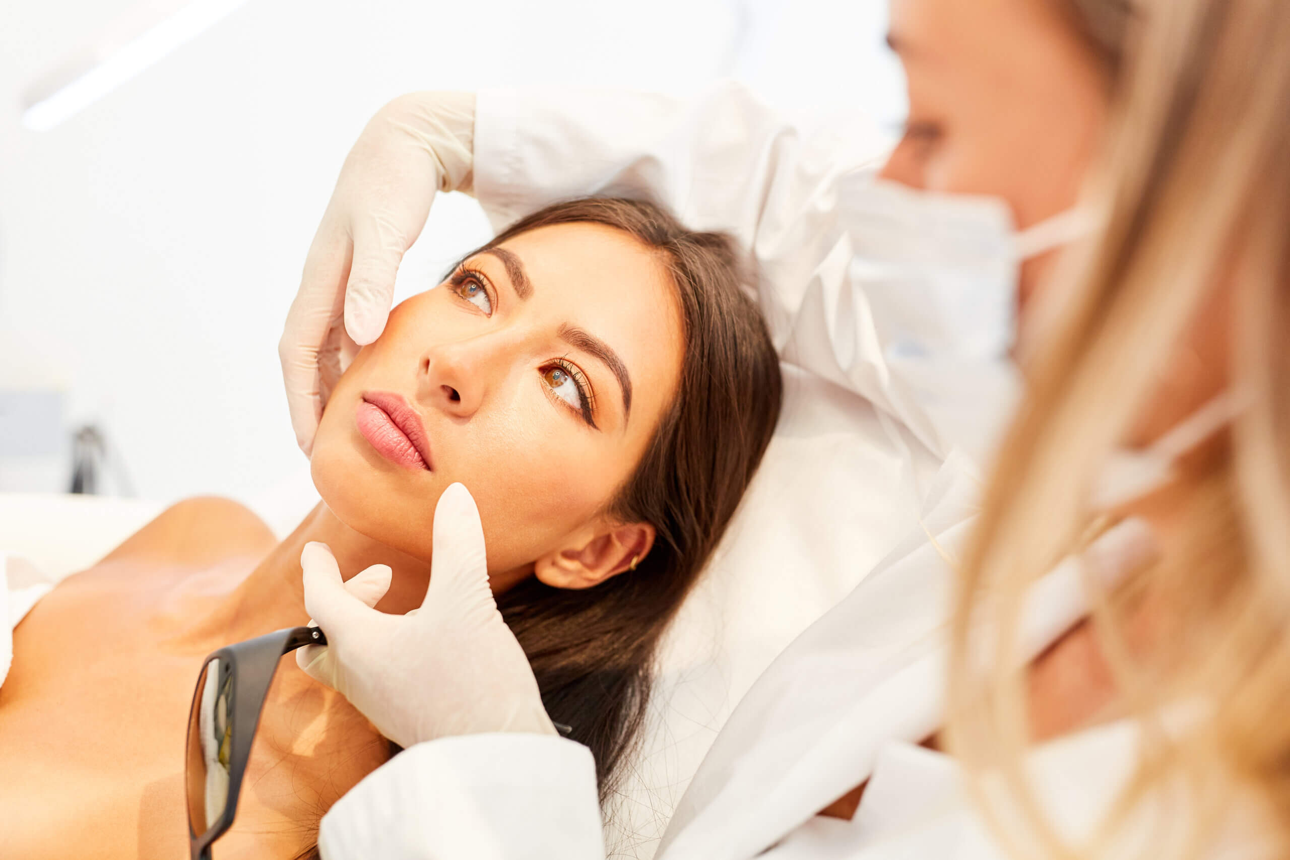 Clinician examining a patient’s face during a cosmetic consultation.