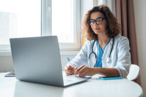 Clinician using a laptop during a remote consultation.