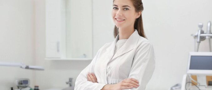 woman in white coat arms crossed posed inside a lab clinic