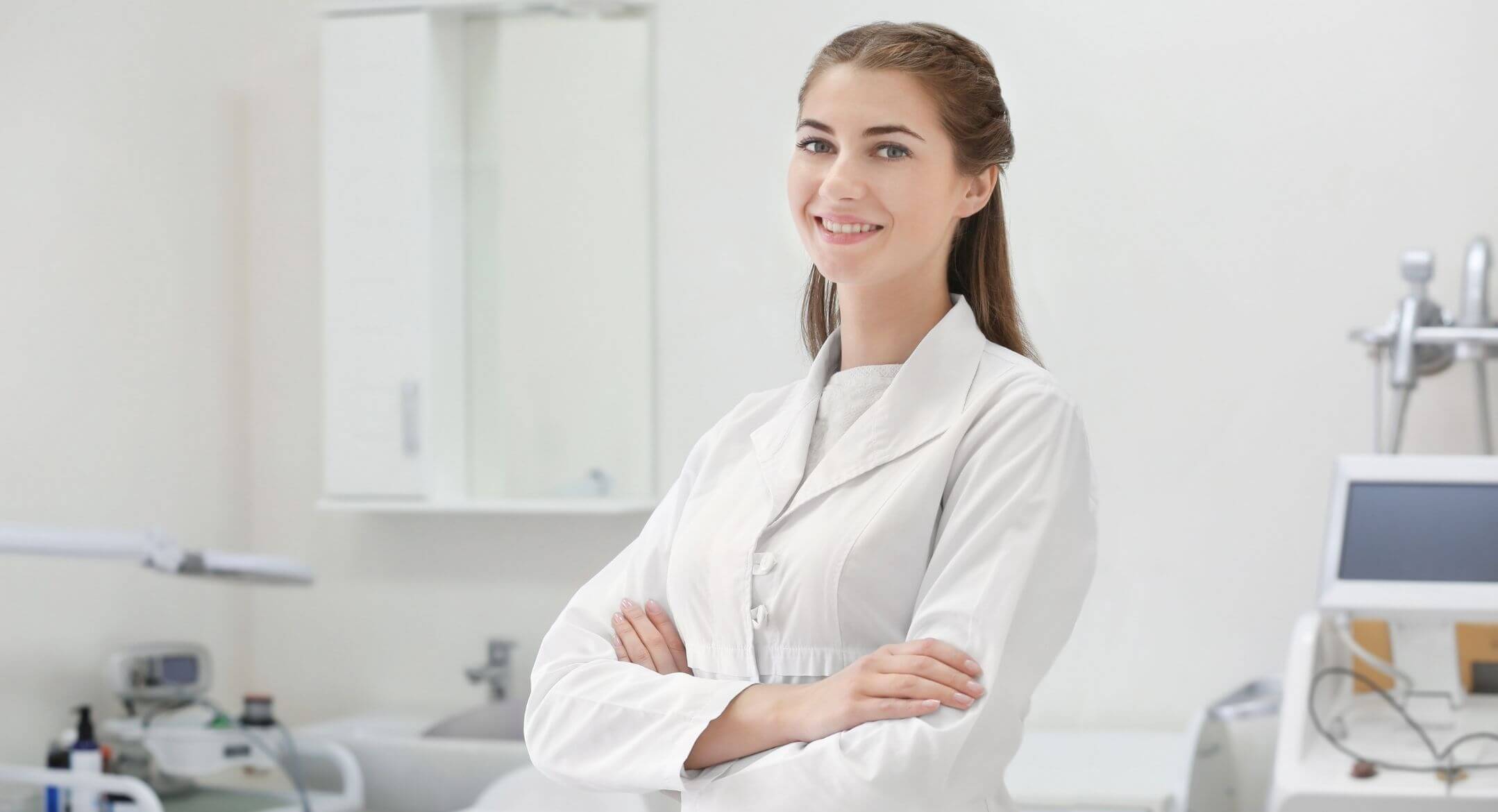woman in white coat arms crossed posed inside a lab clinic