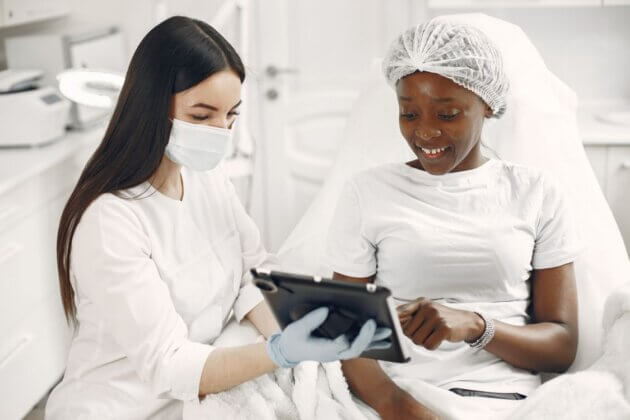 Dermatology clinician and patient reviewing a tablet.
