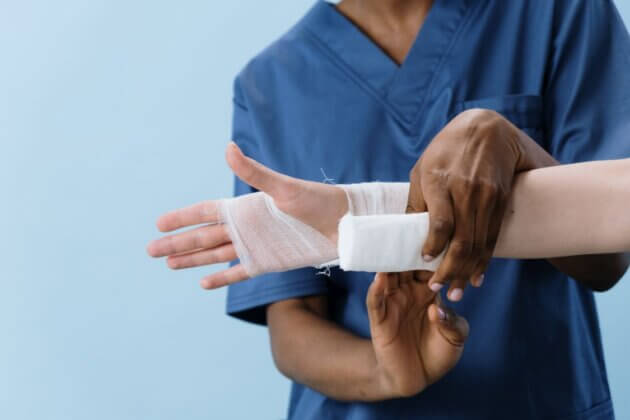 Healthcare professional wrapping a bandage around a hand.