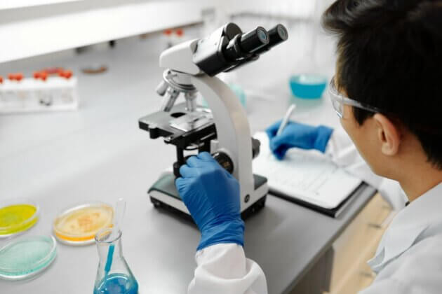 Laboratory researcher examining a sample through a microscope.