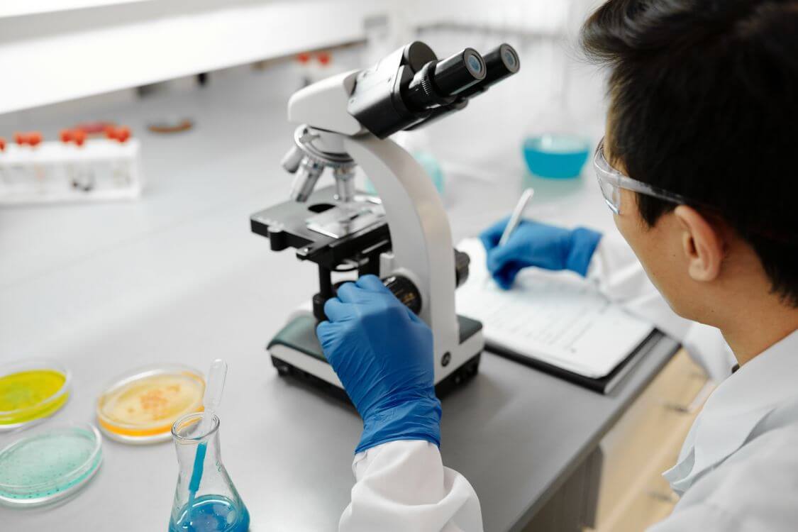 Laboratory researcher examining a sample through a microscope.